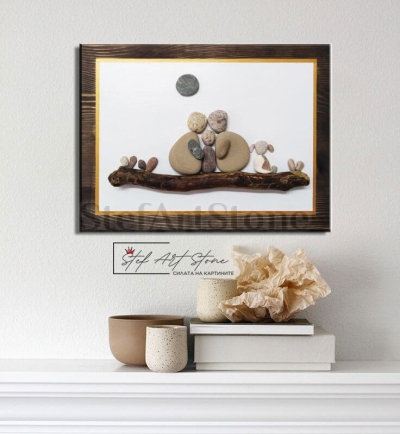 Картина с камъни на семейство с дете и куче, поставена върху дървена основа.