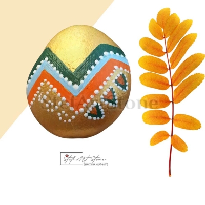 Ръчно рисуван камък с преобладаващо златно и линии от зелено, светло синьо и оранжево