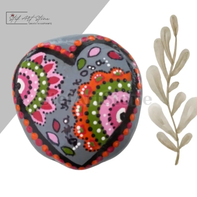 Ръчно рисувано морско камъче с изящно изрисувано сърце, украсено с орнаменти в оранжево, зелено, розово и бяло, и персонализиран надпис с име