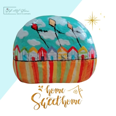 Рисуван камък с разноцветни къщички и три хвърчила във весели цветове.